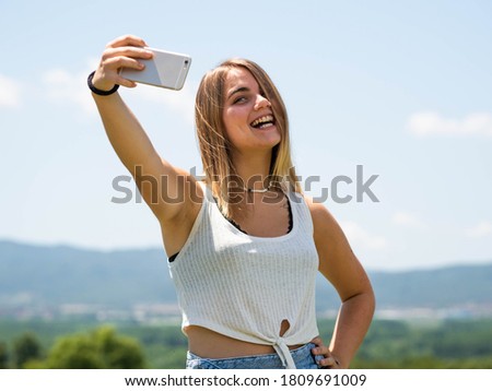A shallow focus shot of a Caucasian female taking a selfie in nature