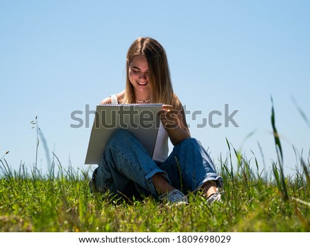 A Caucasian female sitting and drawing in nature