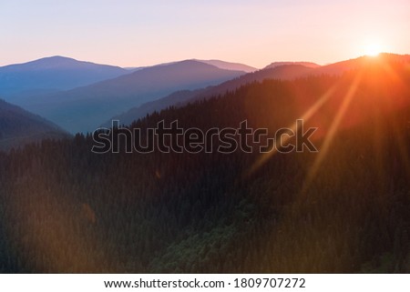 Great view of colorful sunrise in the mountains backlight glow against the sunlight with sun flare and bokeh. Concept of the awakening wildlife, emotional experience in your soul. Retro effect.