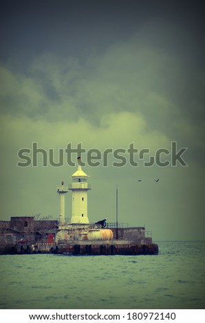 Vintage picture. Old lighthouse at storm weather with flying birds. Crimea, Ukraine