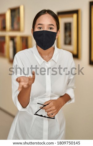 woman visitor wearing an antivirus mask in museum looking at pictures