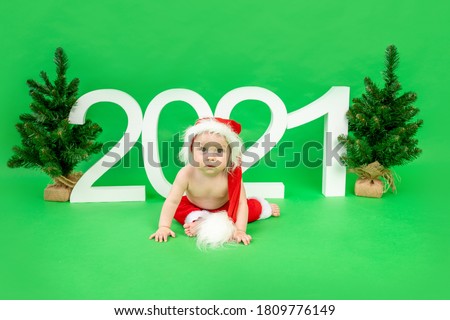 little baby girl sitting on a red sled in a Santa hat on a white isolated background with a snowman, happy new year 2021, space for text
