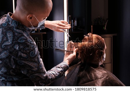 Hairdresser styling a customer's hair with scissors