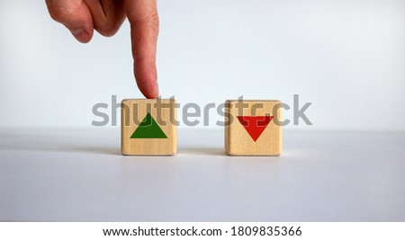 Hand making a choice between two cubes on white background. Arrows changes the direction of an arrow symbolizing that the interest rates are going down or vice versa . Business concept. Copy space.