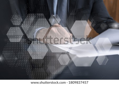 Businessman in suit signs contract. Double exposure with abstract technology hologram. Man signing agreement on research and analysis of high-tech industry.