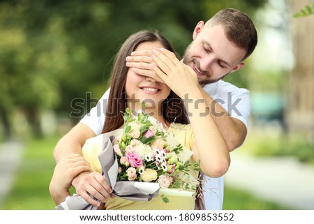 Happy young couple with bouquet of flowers in the park