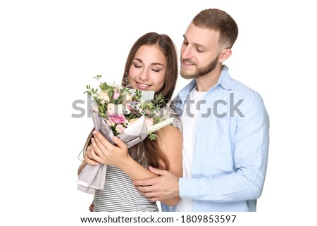 Happy young couple with bouquet of flowers on white background