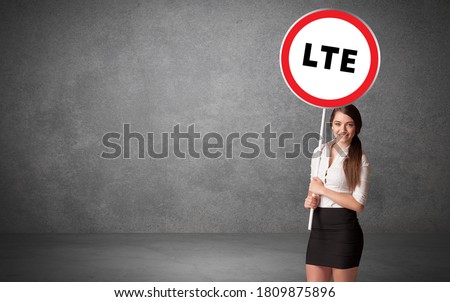 Young business person holdig traffic sign with LTE abbreviation, technology solution concept