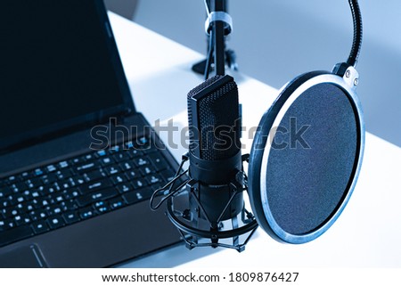 Microphone next to a laptop. Sound recording equipment. Concept - working musto radio host. Equipment for a radio host. Foam pop filter in front of microphone. Sound recording services.