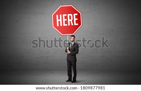 Young business person holding road sign with HERE inscription, new rules concept