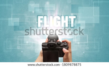 Close-up of a hand holding digital camera with FLIGHT inscription, traveling concept