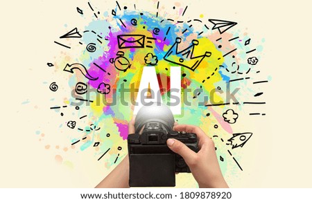 Close-up of a hand holding digital camera with abstract drawing and AI inscription