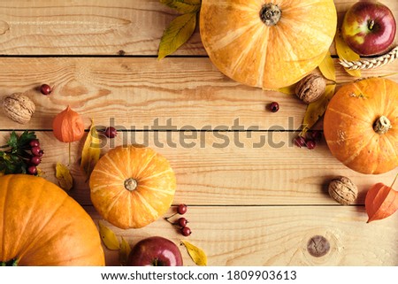 Autumn composition. Pumpkins, fallen leaves, apples, red berries, walnuts on wooden table. Happy Thanksgiving day, Autumn fall concept. Flat lay, top view, copy space