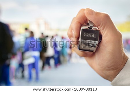 Hand held tally counter counting headcount of people in a queue Royalty-Free Stock Photo #1809908110