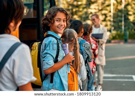 Back to school. Pupils of primary school with teacher near school bus. Happy children ready to study. Royalty-Free Stock Photo #1809913120