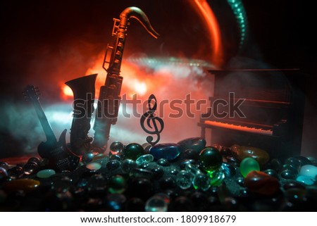 Music concept. Musical symbol treble clef stainless steel miniature with colorful toned light on foggy background. Musical instruments in lowlight. Selective focus