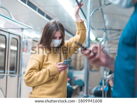 people with smartphones standing in a subway car.
