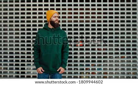 City portrait of handsome hipster guy with beard wearing green (watercolor) blank hoodie or sweatshirt with space for your logo or design. Mock up for print Royalty-Free Stock Photo #1809944602