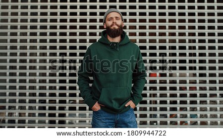 City portrait of handsome hipster guy with beard wearing green (watercolor) blank hoodie or sweatshirt with space for your logo or design. Mock up for print