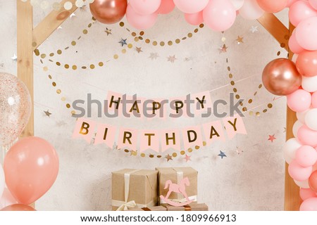 Birthday decorations - gifts, toys, balloons, garland and figure for little baby party on a white wall background.