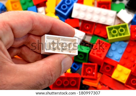 Mans hand holds a red toy block against mix of building blocks background. concept photo of imagination, creativity, planning and ideas.No people. Copy space
