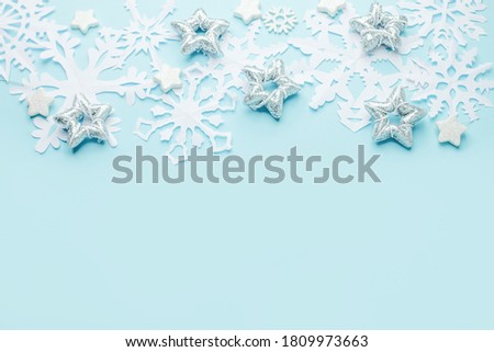 Christmas or winter composition. Frame made of paper cut snowflakes and silver stars on pastel blue background. Christmas, winter, new year concept. Flat lay, top view, copy space