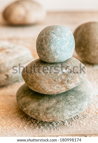 Stacked natural rounded weathered Zen stones with scattered beach sand conceptual of a spa, wellness, spirituality and meditation