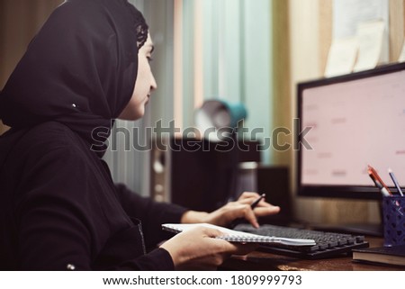 Middle eastern female entrepreneur. Busy Arabian businesswoman. A middle-aged woman in traditional Arabian clothing hijab or abaya working on PC