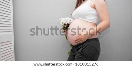 Pregnant woman holds hands on belly on a white background. Pregnancy, maternity, preparation and expectation concept. Close-up, copy space. Beautiful tender mood photo of pregnancy.