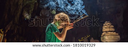 Young boy praying in a Buddhist temple holding incense Huyen Khong Cave with shrines, Marble mountains, Vietnam BANNER, LONG FORMAT