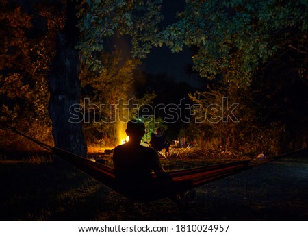 Amazing scene in night camping -man in hammock on bonfire background