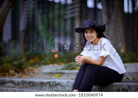
Beautiful black haired woman wearing a black hat in white dress