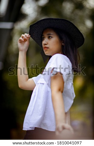 
Beautiful black haired woman wearing a black hat in white dress