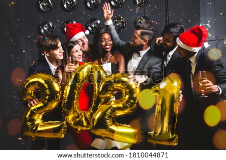 Beautiful young people at a corporate party holding balloons 2021. Happy New Year celebration. Club party with friends