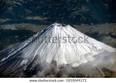 The summit of a volcano that snowed from between the clouds seen from the sky. It is a mountain symbolizing Japan.