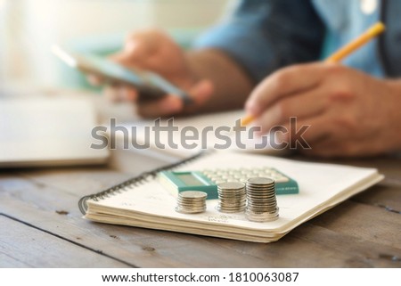 Stacks of coins on a wooden table with a calculator. Taxing, home accounting or credit analysis for mortgage payment concept Royalty-Free Stock Photo #1810063087