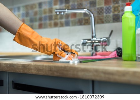 woman wearing rubber gloves and cleaning the kitchen cabinets or surface. cleaning concept