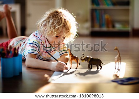 Child shadow drawing animals. Kids play at home. Fun crafts for kindergarten children. Little boy painting giraffe and elephant in sunny bedroom. Games and art during coronavirus quarantine lockdown.