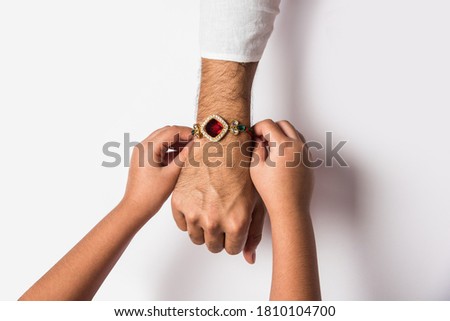 Close up top view of female hands tying colorful rakhi on her brother’s hand isolated on white background on Raksha Bandhan Festival Royalty-Free Stock Photo #1810104700
