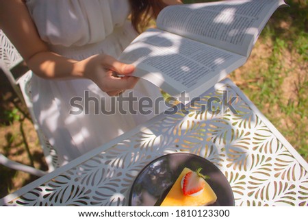 Women hands holding the book to reading in the garden at cafe. Relaxation and reading concept. Weekend activity concept.