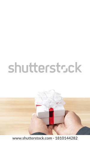 A gift box in the hand of a man wearing a black suit on white background, Concept of happiness in giving gifts to someone special. Isolated.