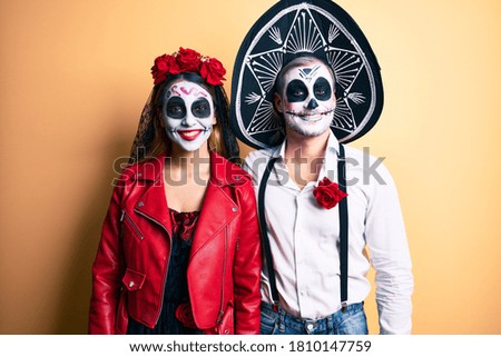 Couple wearing day of the dead costume over yellow with a happy and cool smile on face. lucky person. 