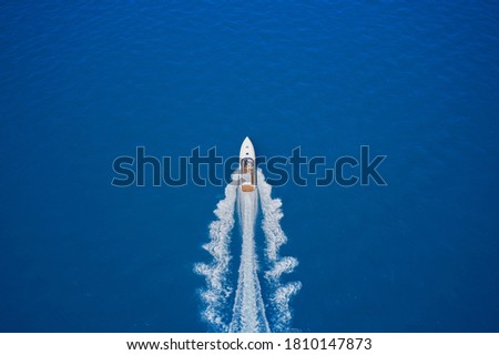Top view of a white boat sailing in the blue sea. luxury motor boat. Aerial view of a boat in motion on blue water. Drone view of a boat sailing at high speed. Royalty-Free Stock Photo #1810147873