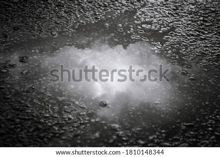 Puddle of water on asphalt road reflecting the sky,dramatic scene after hard rain fall.Selective focus.