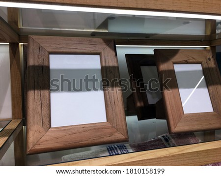 Solid design in natural-colored wood. Designer natural teak wood photo frames on a glass shelf in a decor store. Ideas for a modern interior. Fashion decor. Black irregular wavy resin design