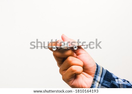 Selective focus picture of hand holding miniature aircraft on white background.