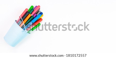 Set multicolored pointed markers in a light blue bucket on a white background, copy space, banner. Drawing felt-tip pens, pencils, artists tools, creativity, leisure, hobby. Colorful school supplies.