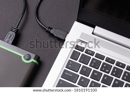 Hard disk and laptop on a black table close-up.