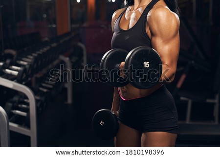 Cropped photo of a well-shaped woman working out using a pair of dumbbells at the gym Royalty-Free Stock Photo #1810198396