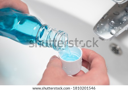 Hand of man Pouring Bottle Of Mouthwash Into Cap. Royalty-Free Stock Photo #1810201546